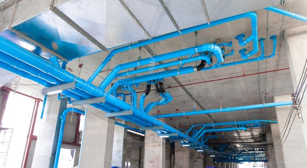 A Bunch of Blue Pipes Are Hanging From the Ceiling of a Building — Affordable Plumbing In Port Macquarie, NSW