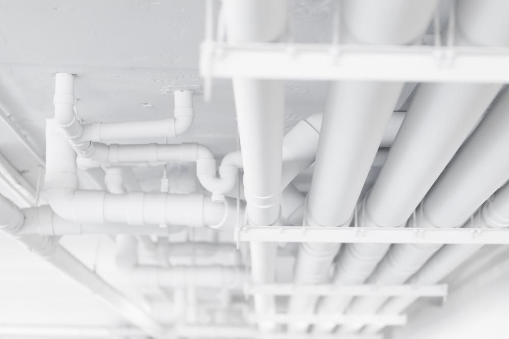 A Bunch of White Pipes Are Hanging From the Ceiling of a Building — Affordable Plumbing In Bonny Hills, NSW