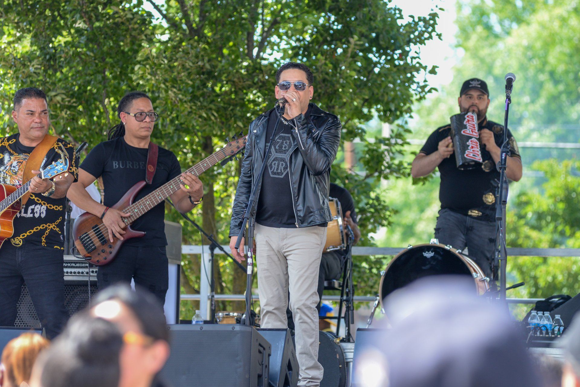 A man is singing into a microphone while standing on a stage in front of a crowd.