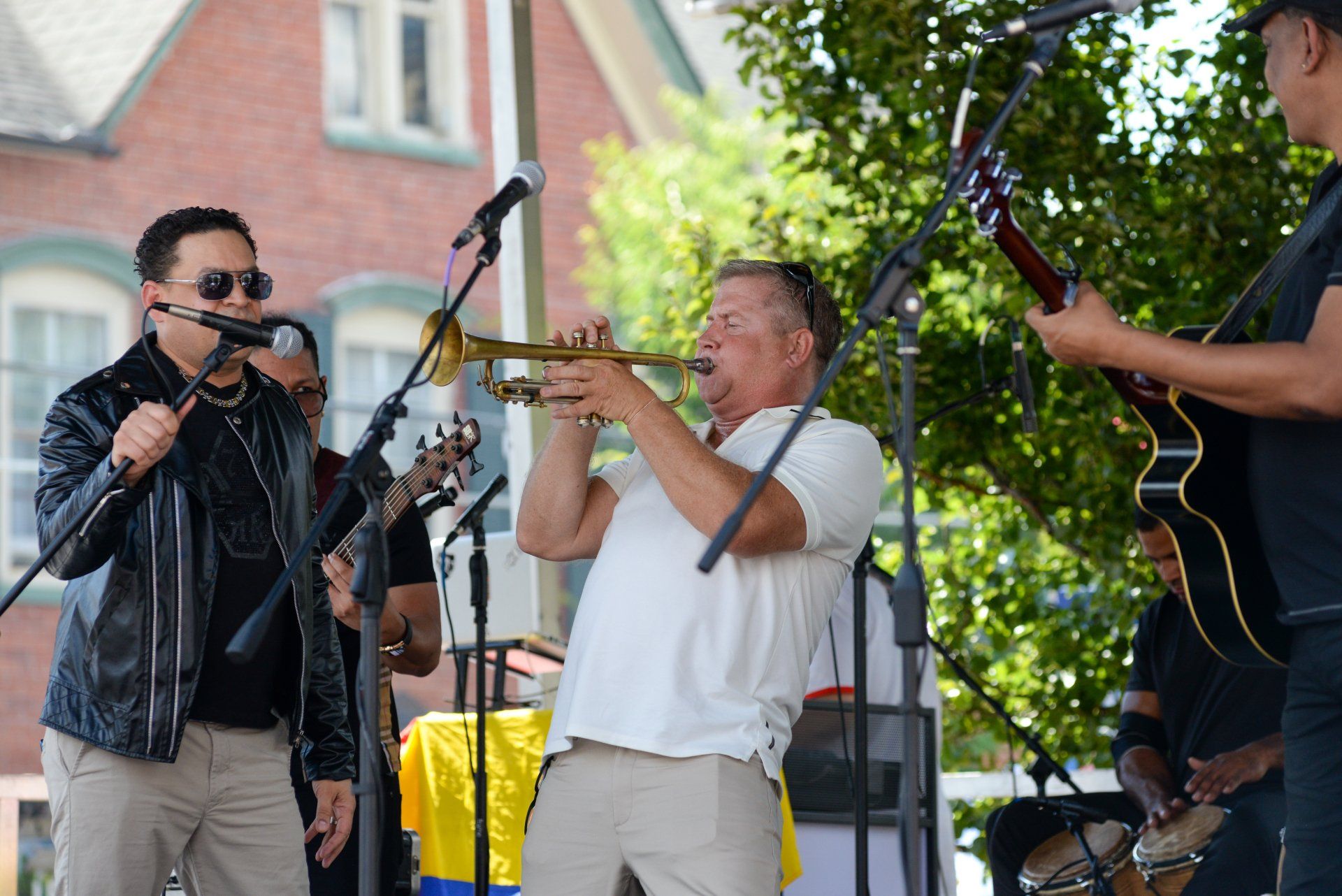 A man is playing a trumpet while another man sings into a microphone