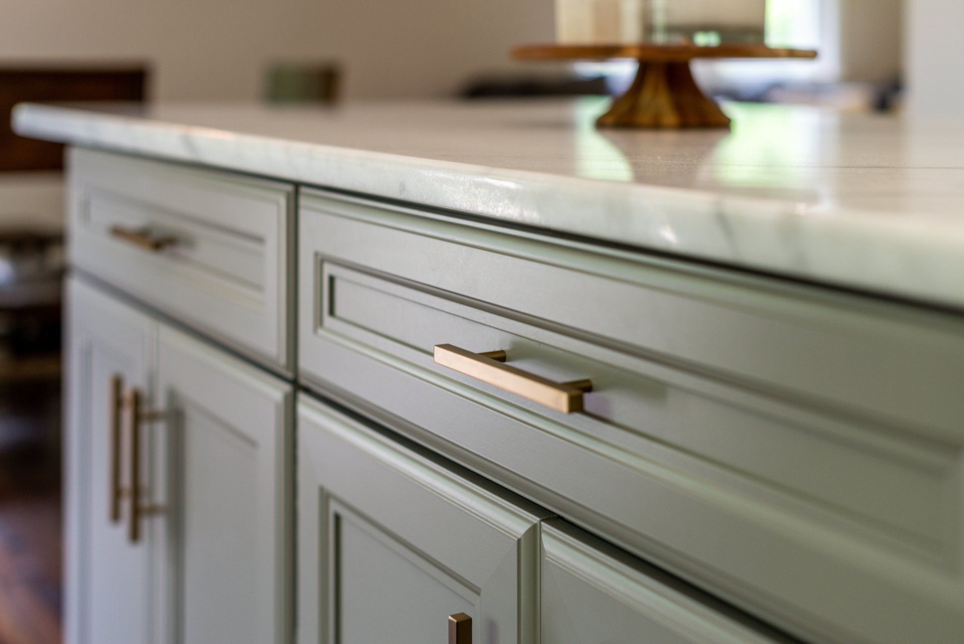 A kitchen with white cabinets and a marble counter top.