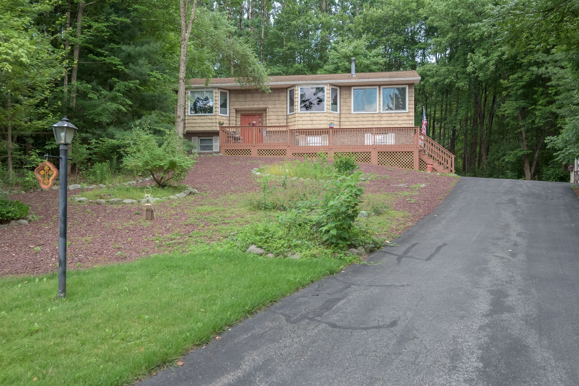 A house with a driveway leading to it is surrounded by trees