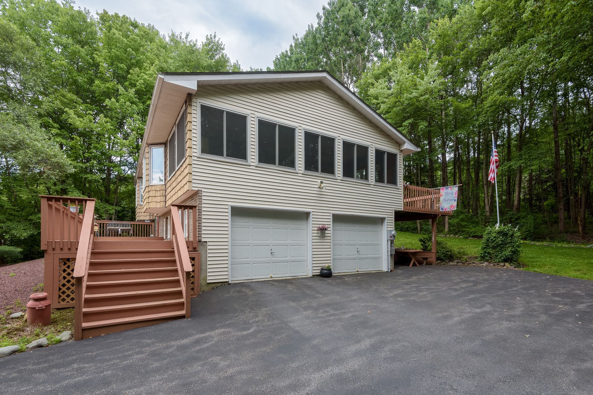 A house with two garages and a deck in the woods