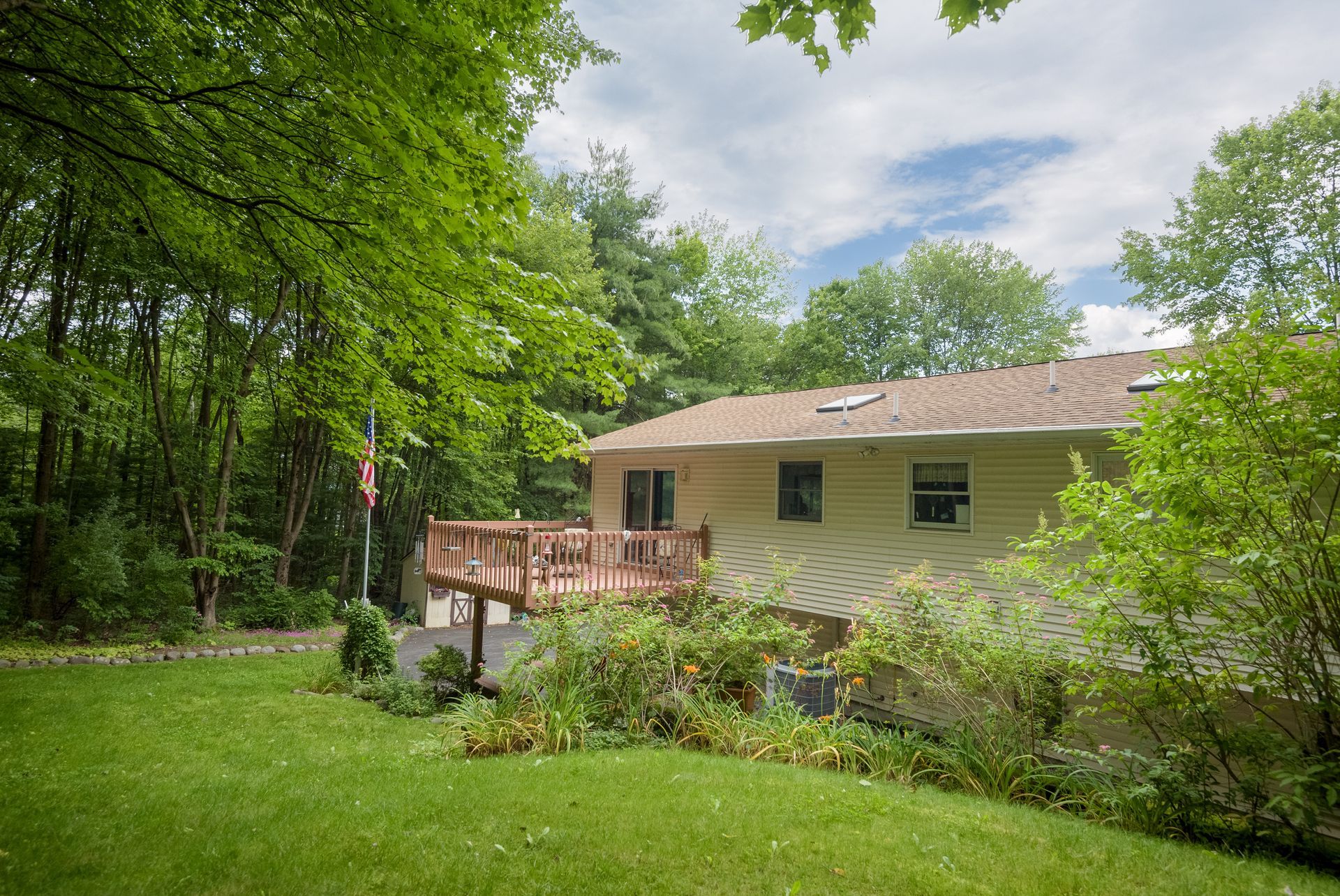 A house with a large deck in the backyard surrounded by trees.