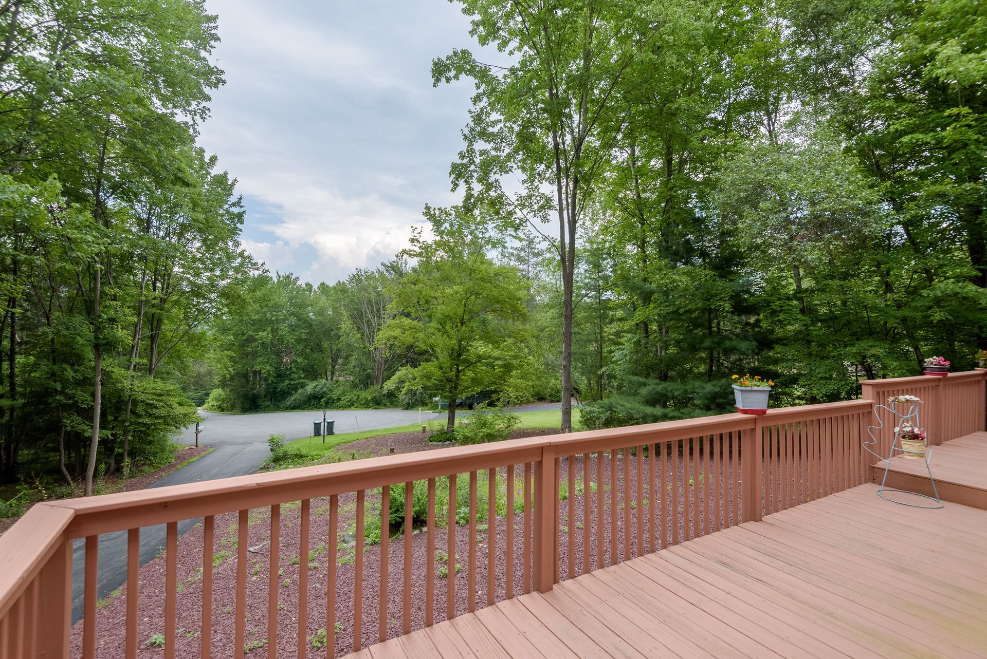 A wooden deck with a view of trees and a road