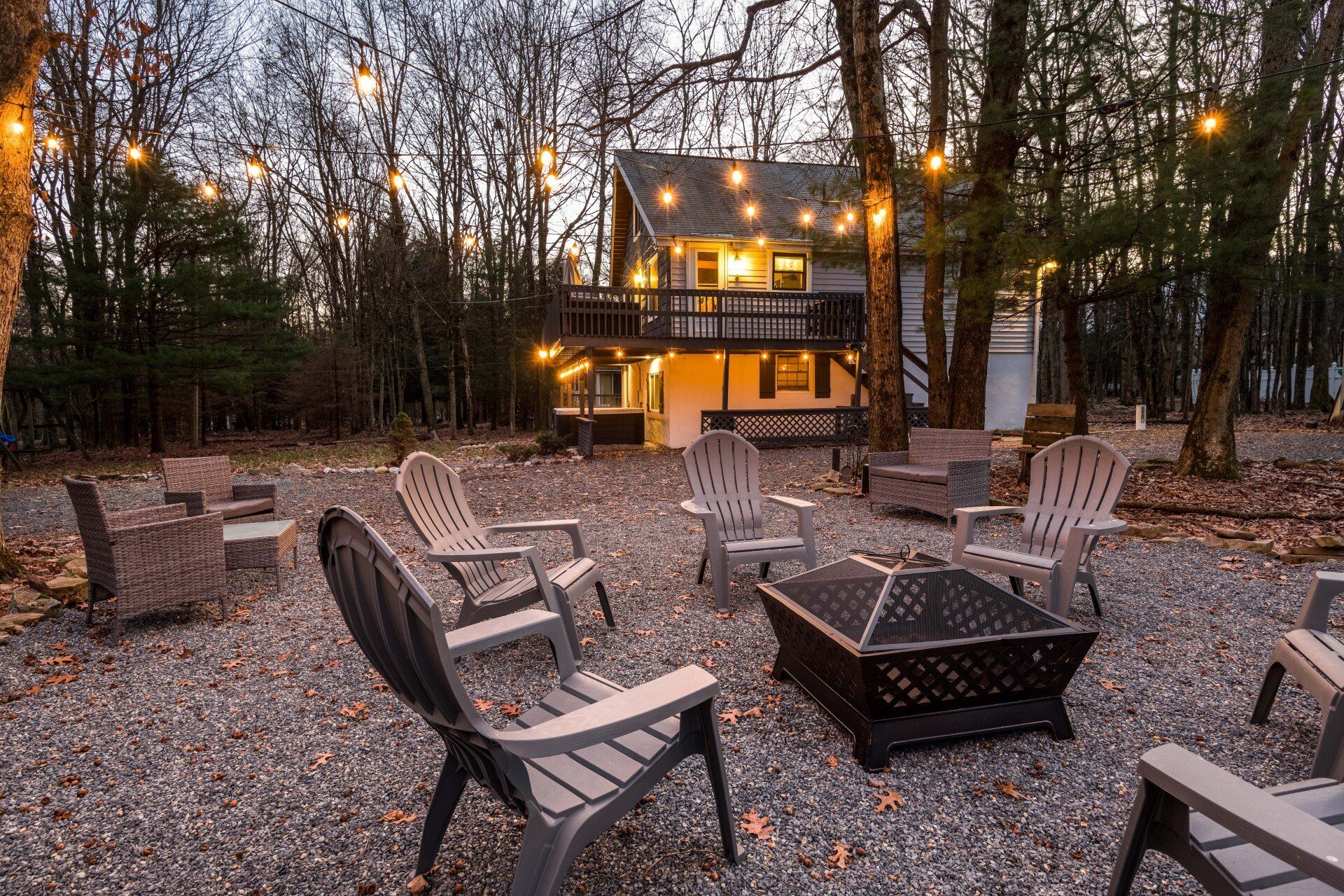A fire pit is surrounded by chairs in front of a house.