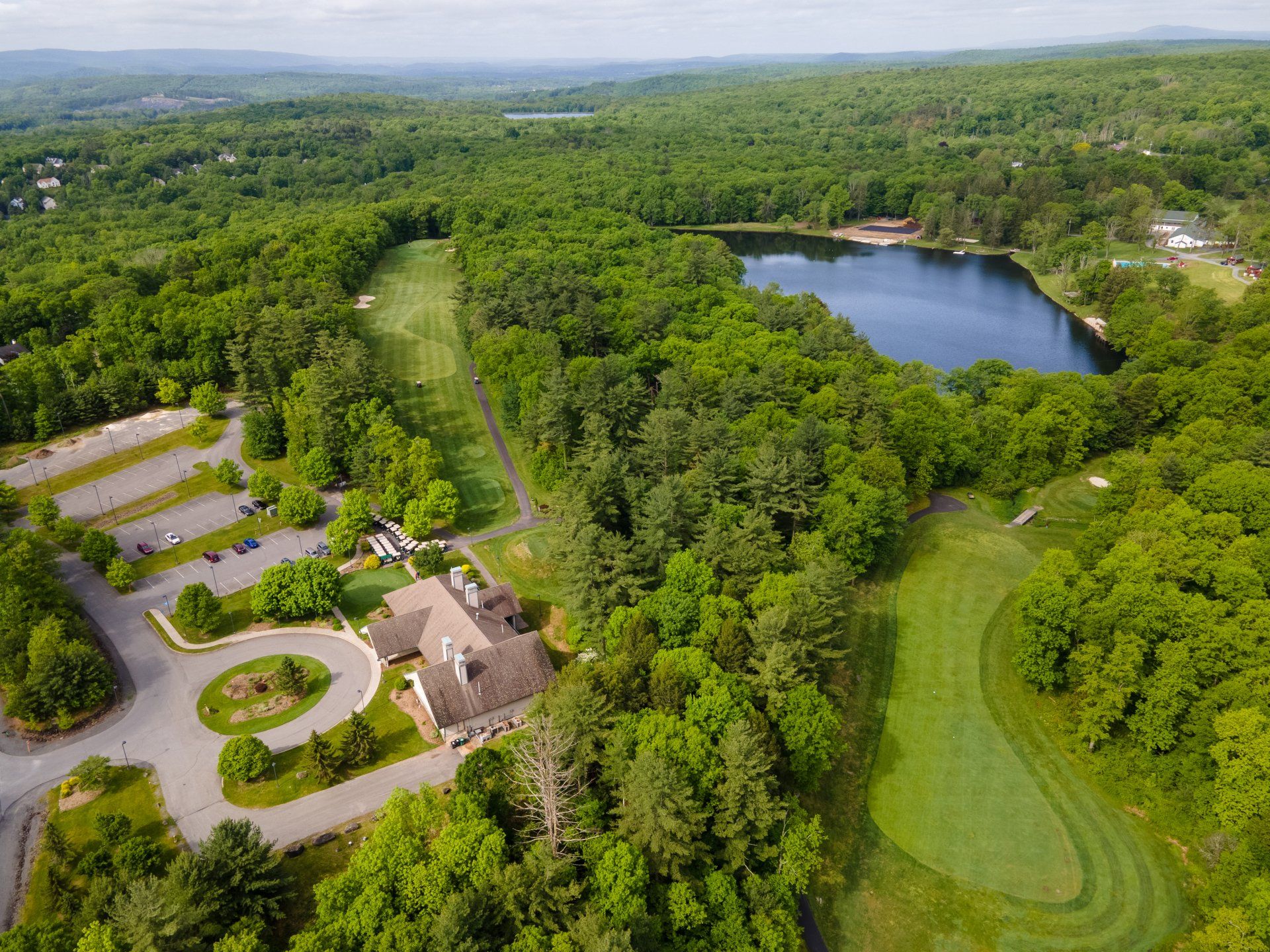 An aerial view of a golf course surrounded by trees and a lake.