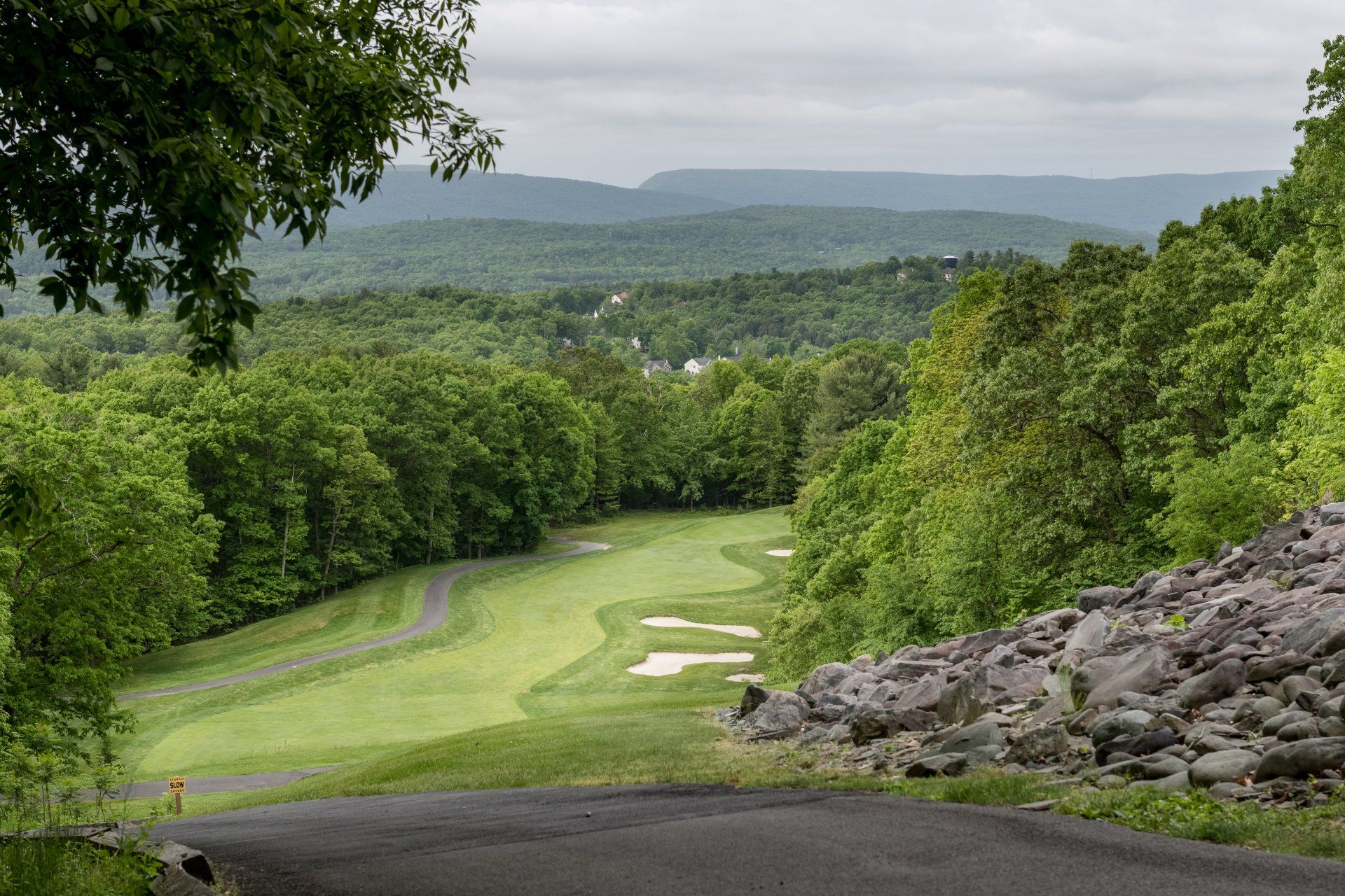 A road leading to a golf course surrounded by trees and rocks.