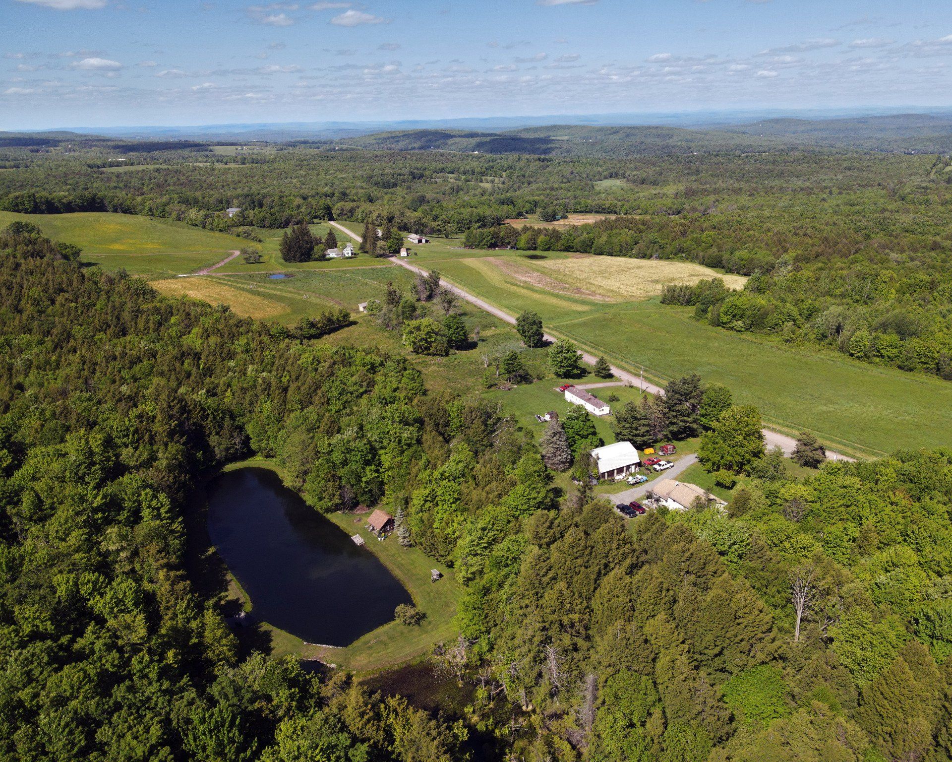 An aerial view of a lake surrounded by trees and fields.