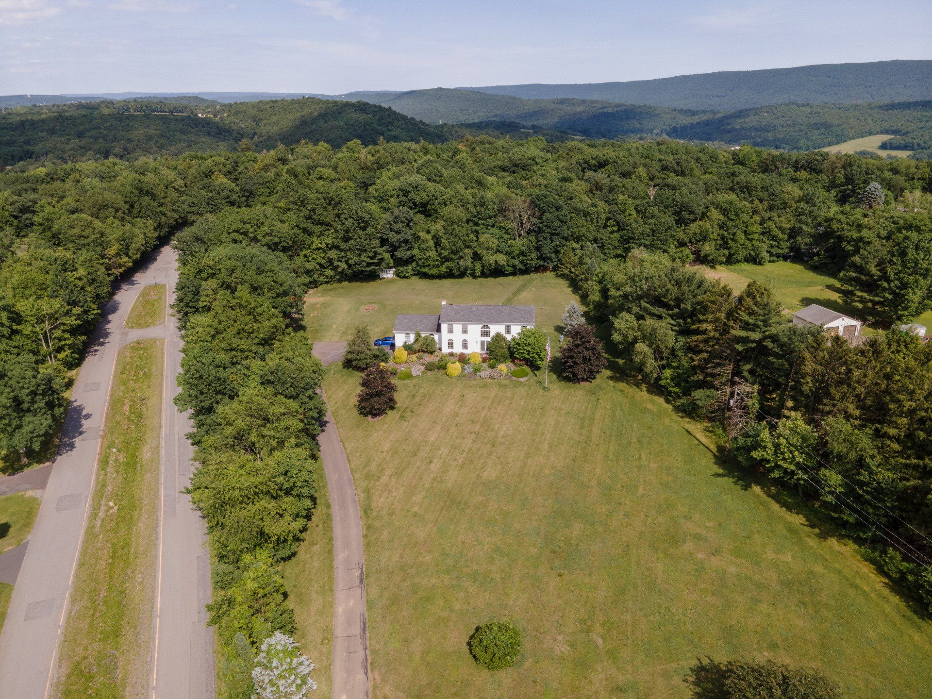 An aerial view of a house surrounded by trees and a road.