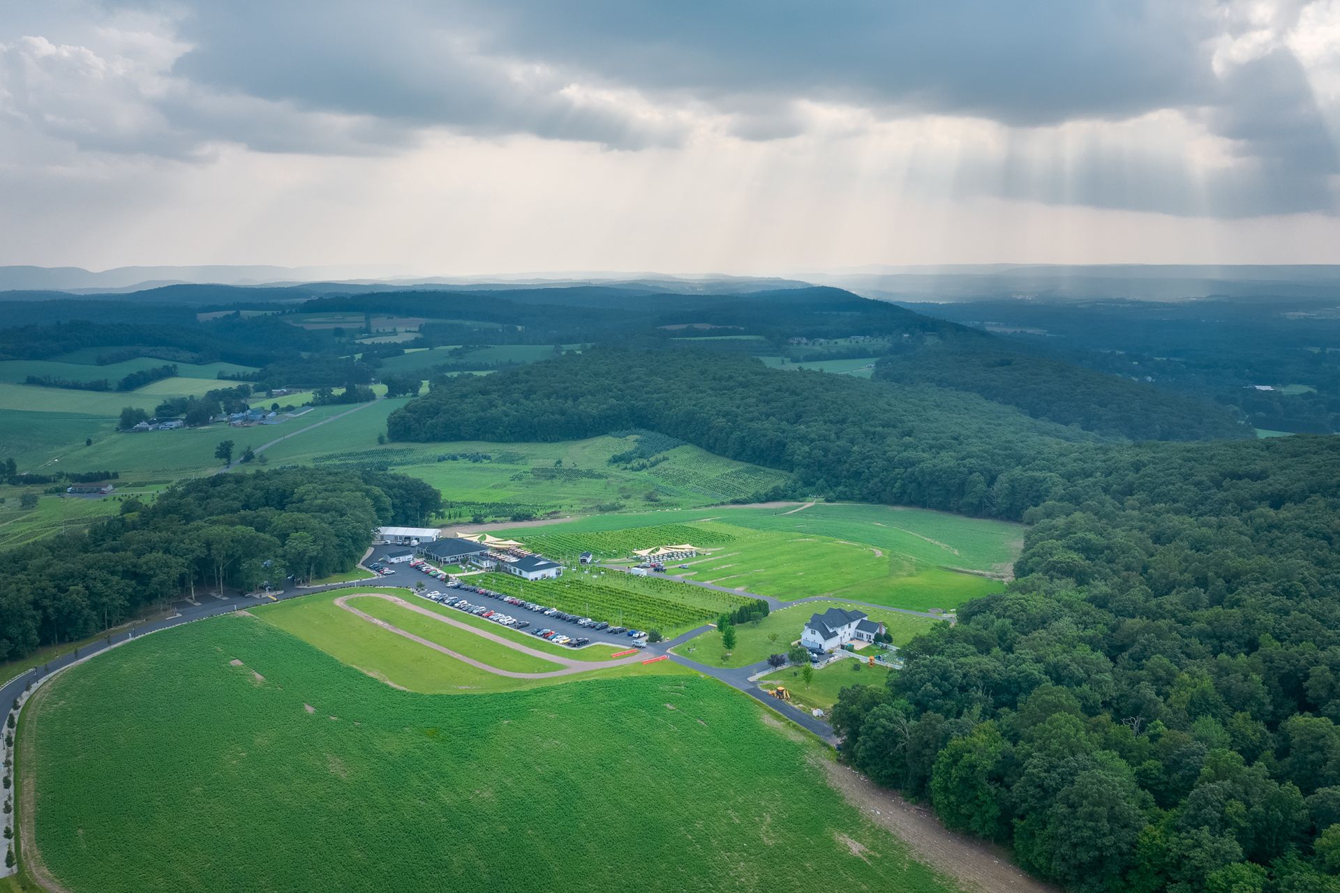 An aerial view of a lush green field surrounded by trees and mountains.