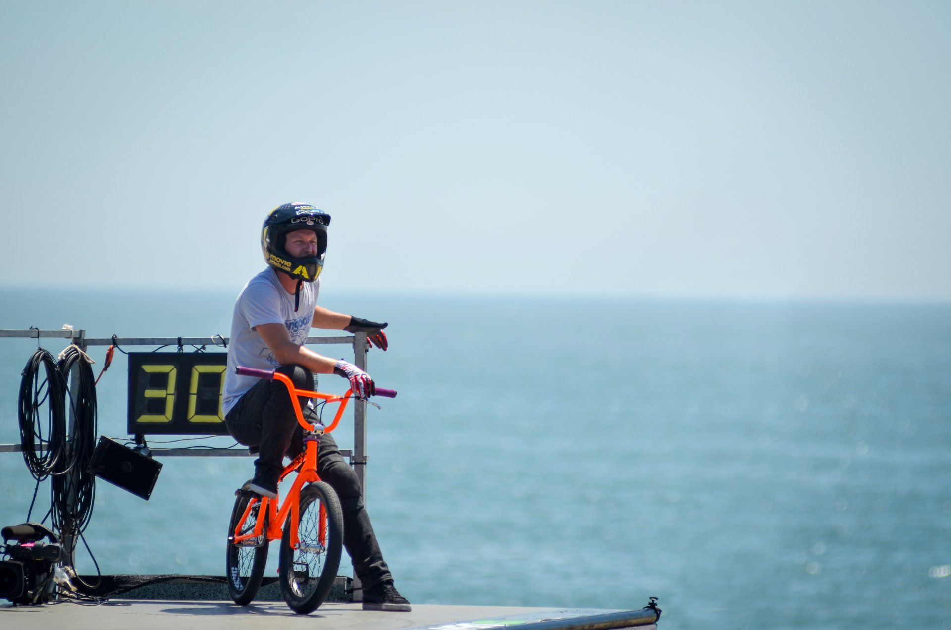 A man is riding a bike on a dock near the ocean.