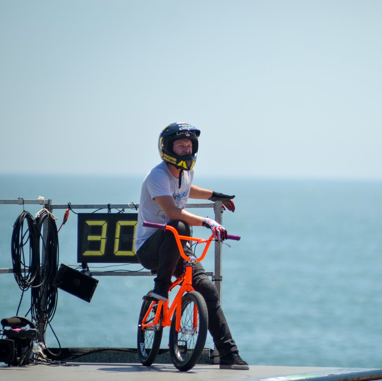 A man is sitting on a bike in front of a sign that says 30