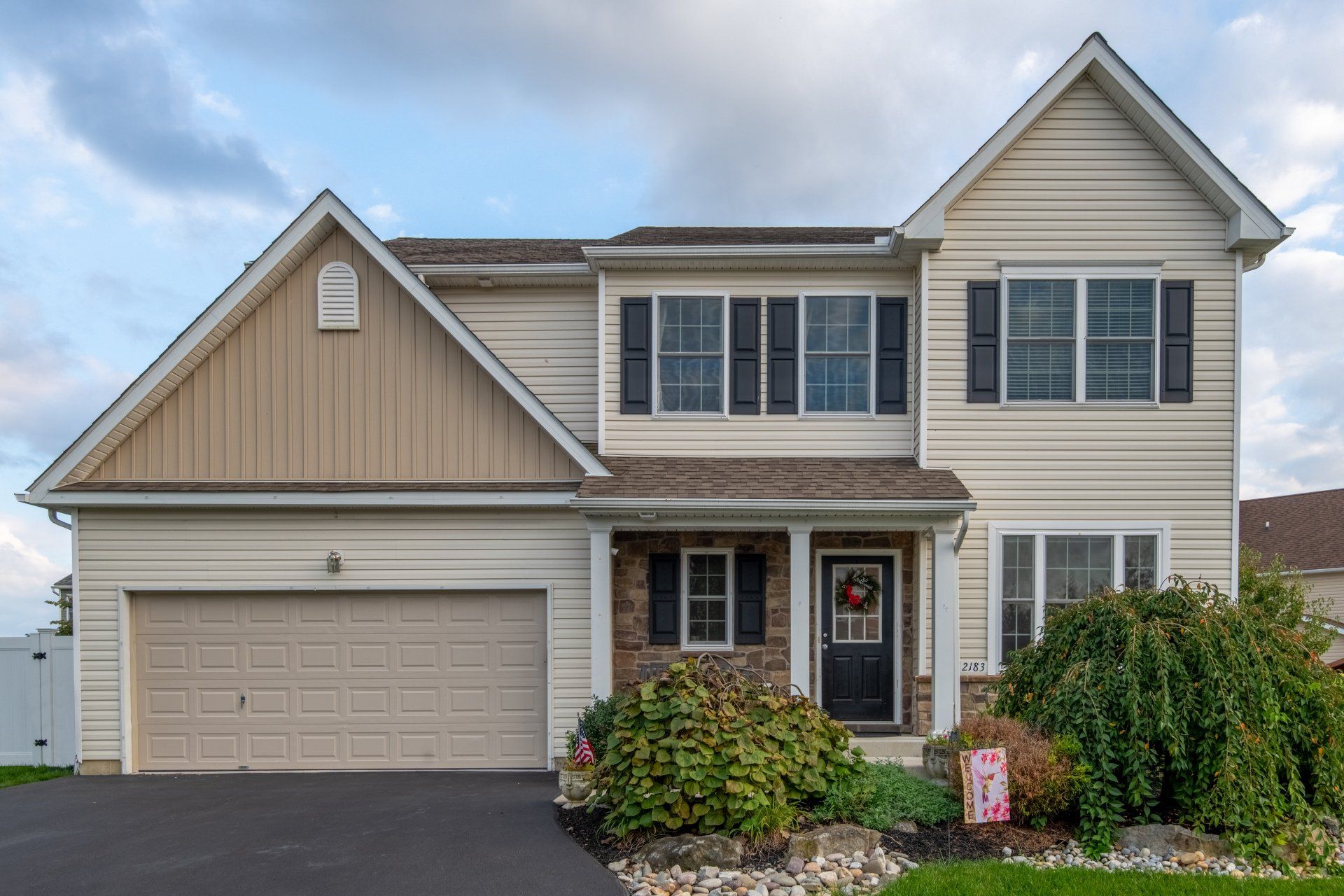 A large white house with a large garage and a wreath on the door.