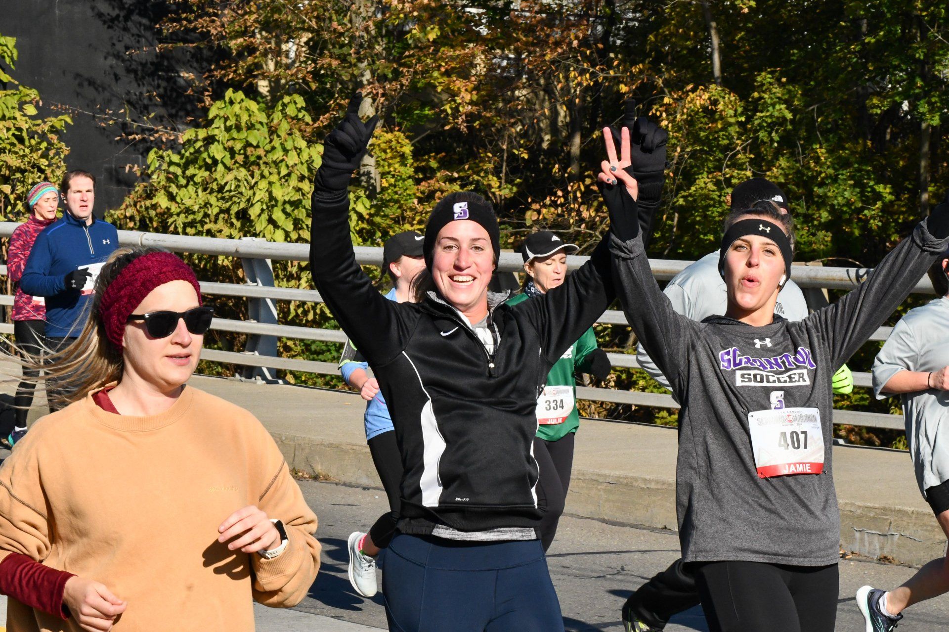 A group of people are running in a race with their arms in the air.