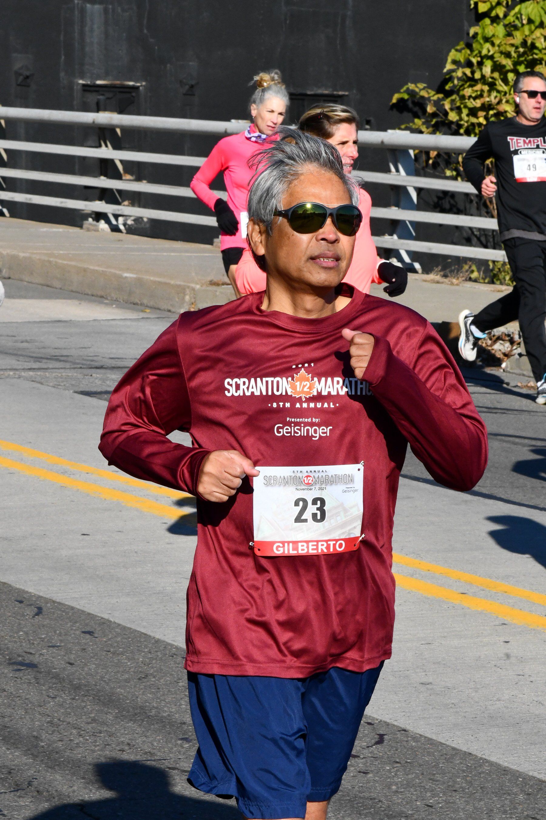 A man in a maroon shirt is running a marathon.