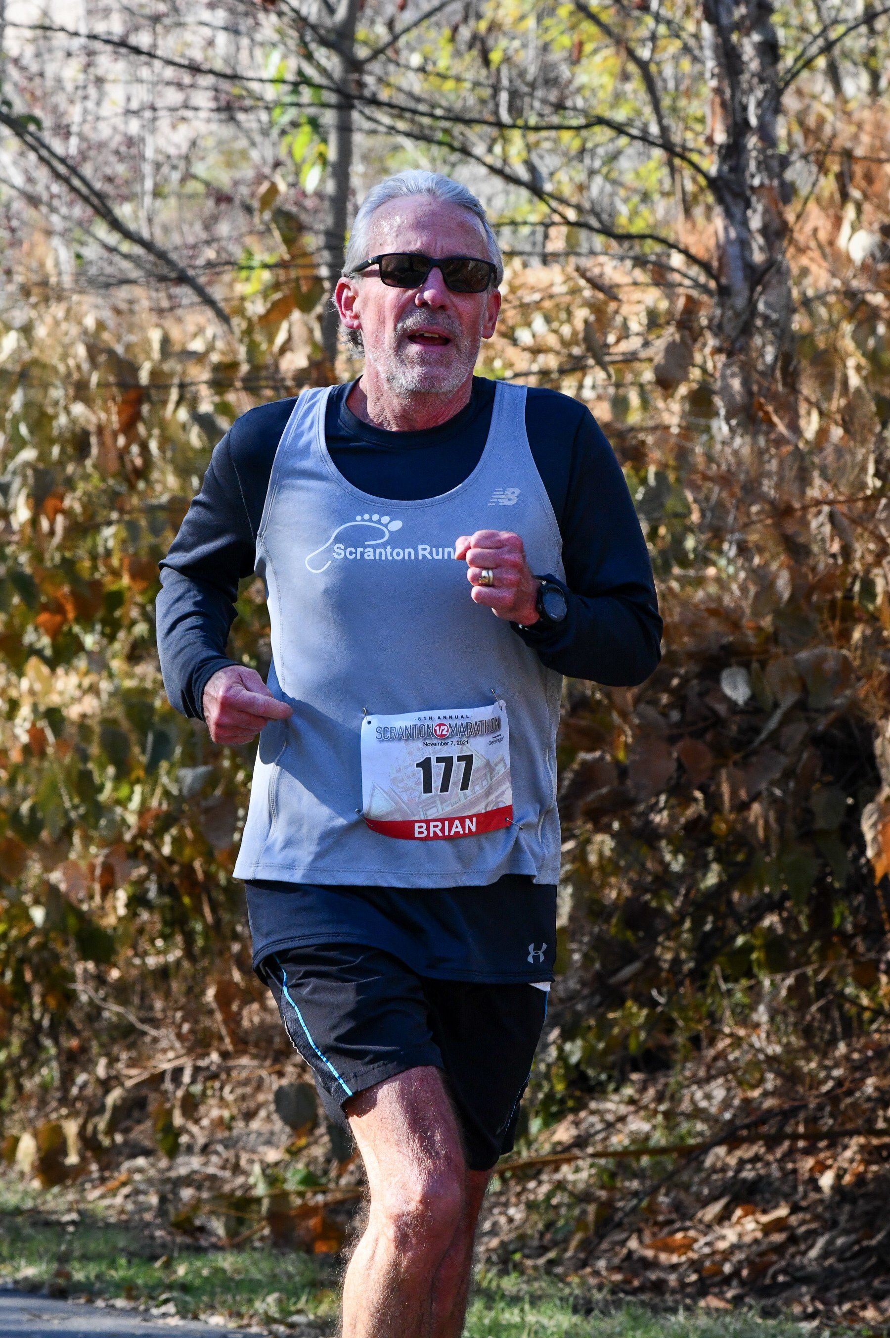 A man with a beard and sunglasses is running a marathon.