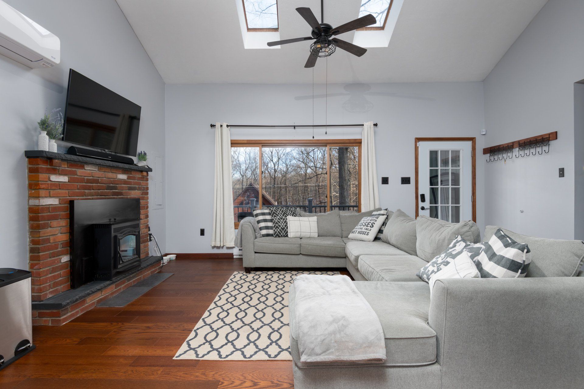 A living room with a couch , fireplace , television and ceiling fan.