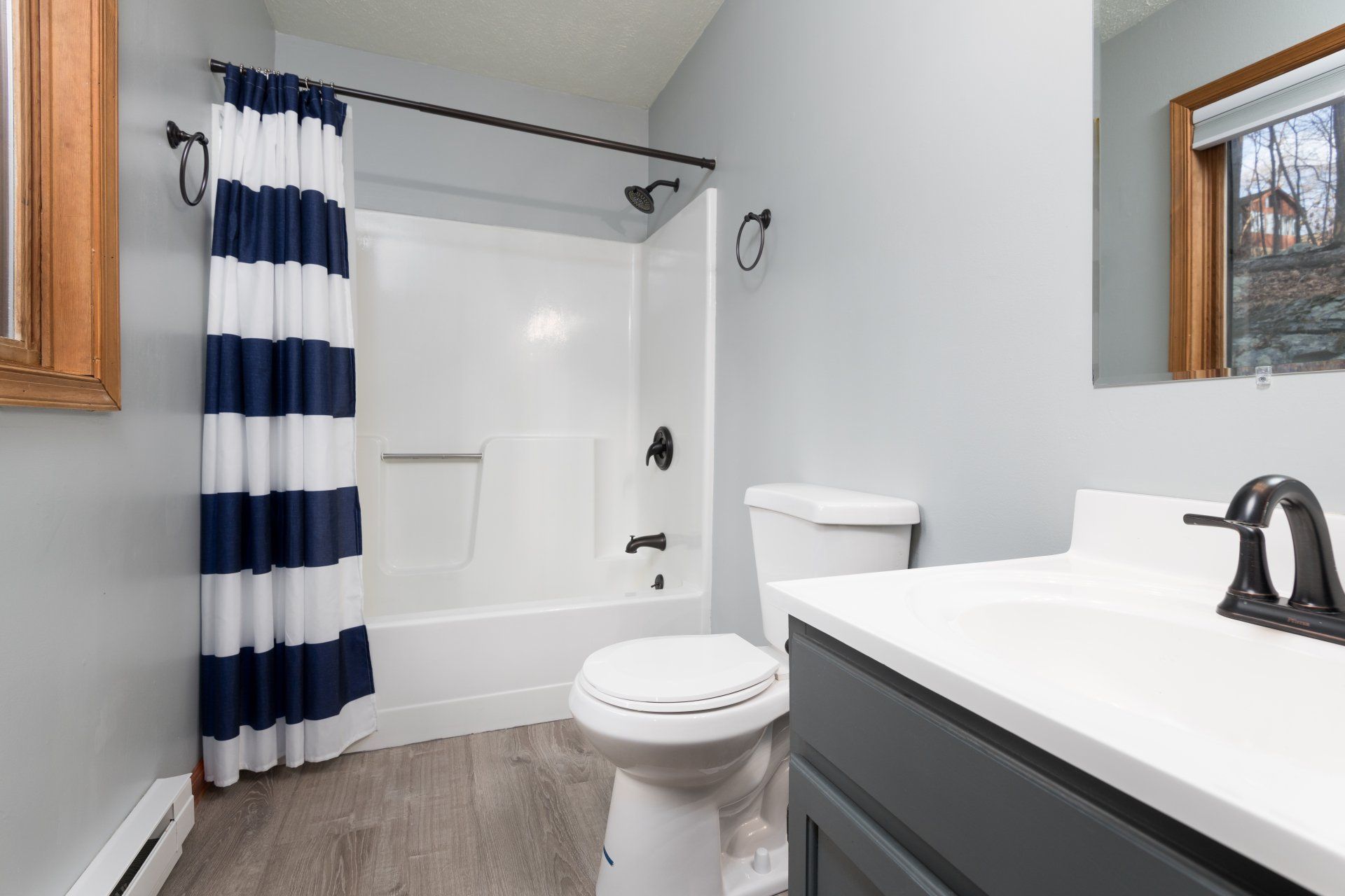 A bathroom with a toilet , sink , shower and striped shower curtain.
