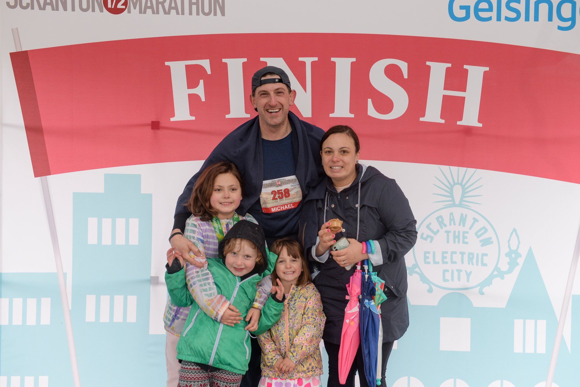 A family is posing for a picture in front of a finish sign.