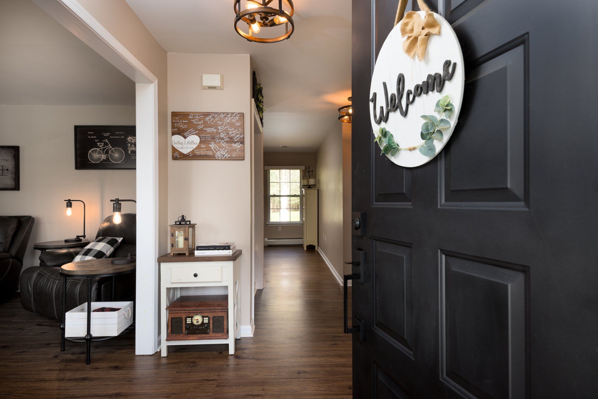 A black door with a welcome sign hanging on it