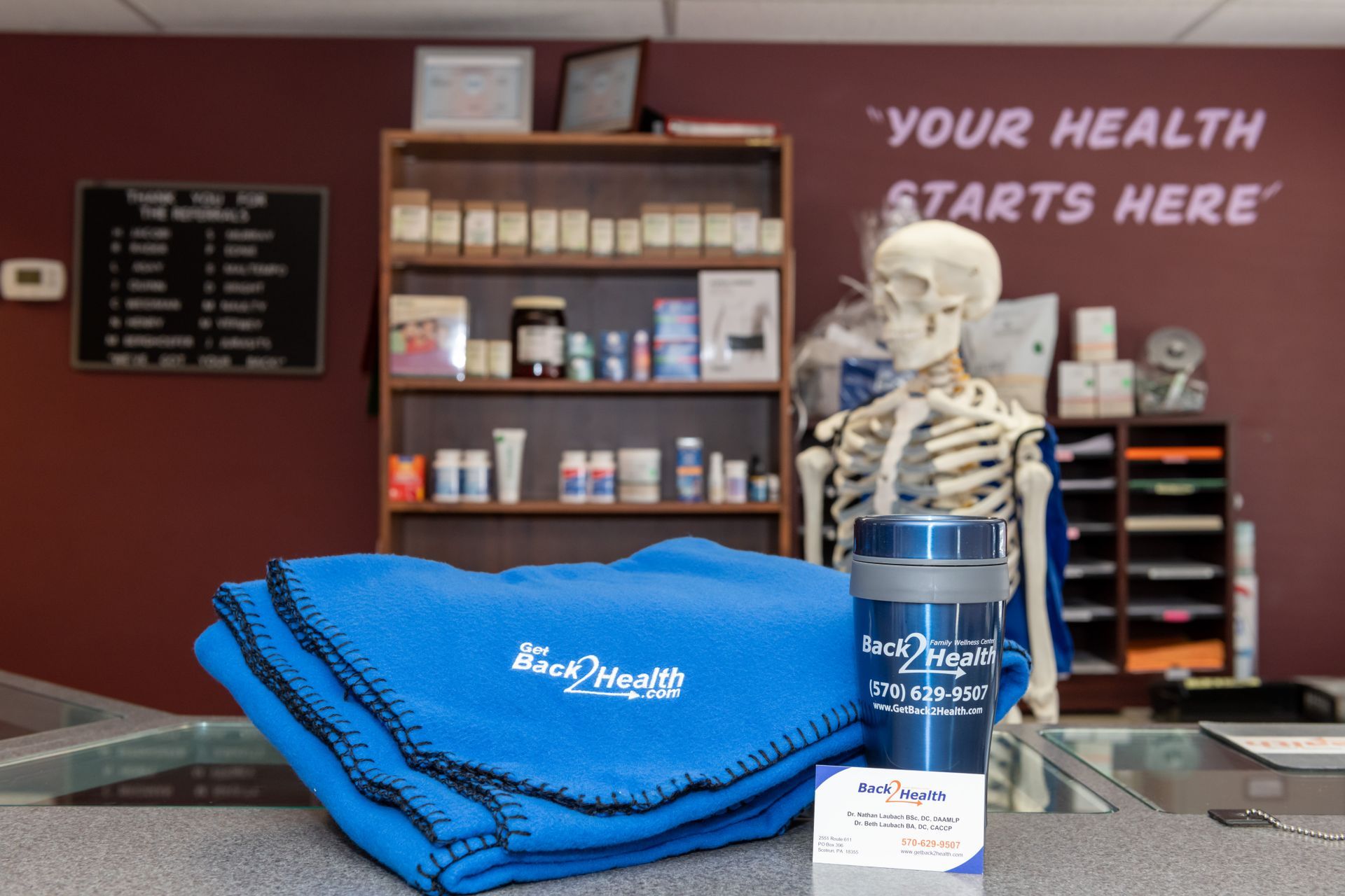 A skeleton sits in front of a sign that says 