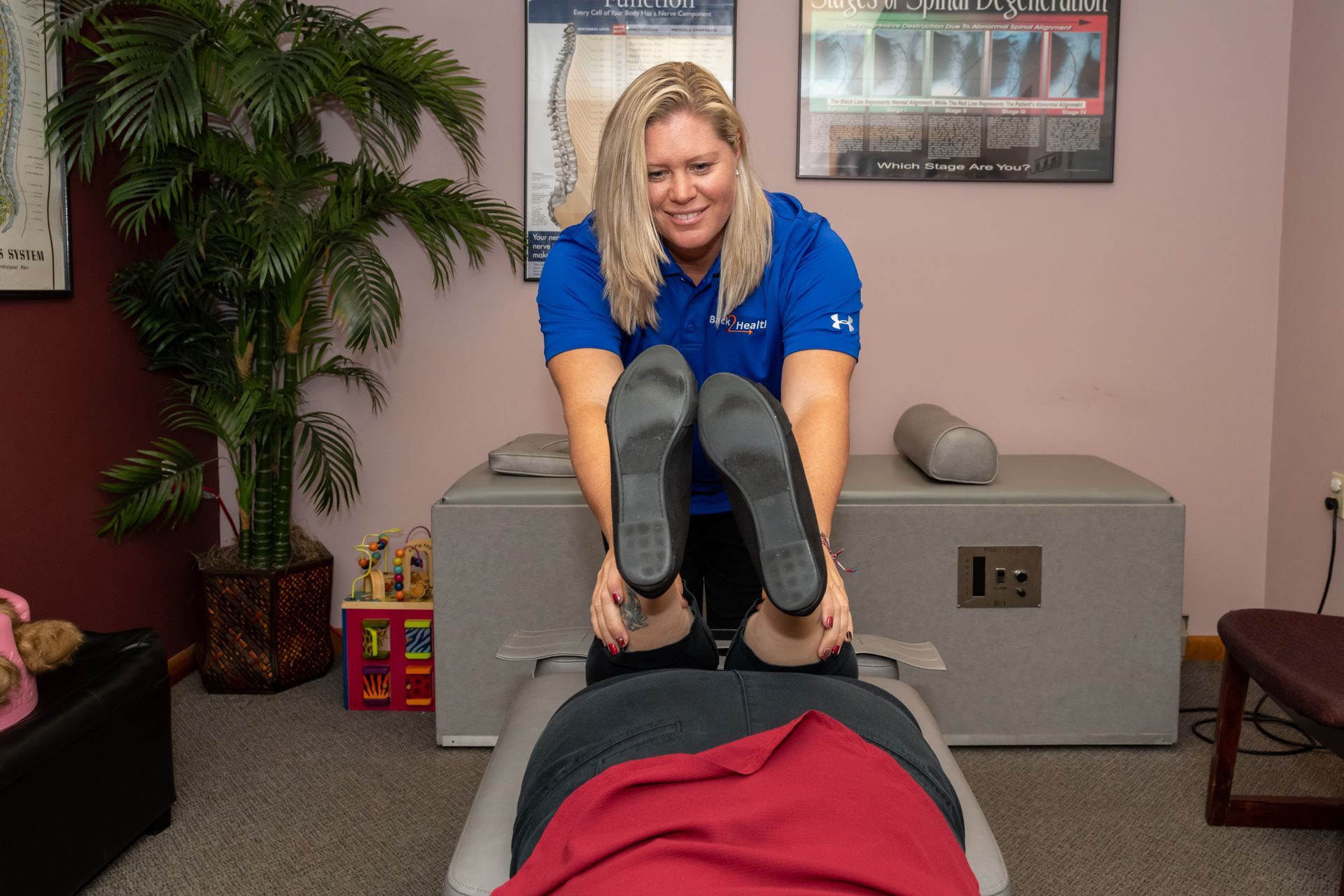 A woman is stretching a man 's legs on a table.