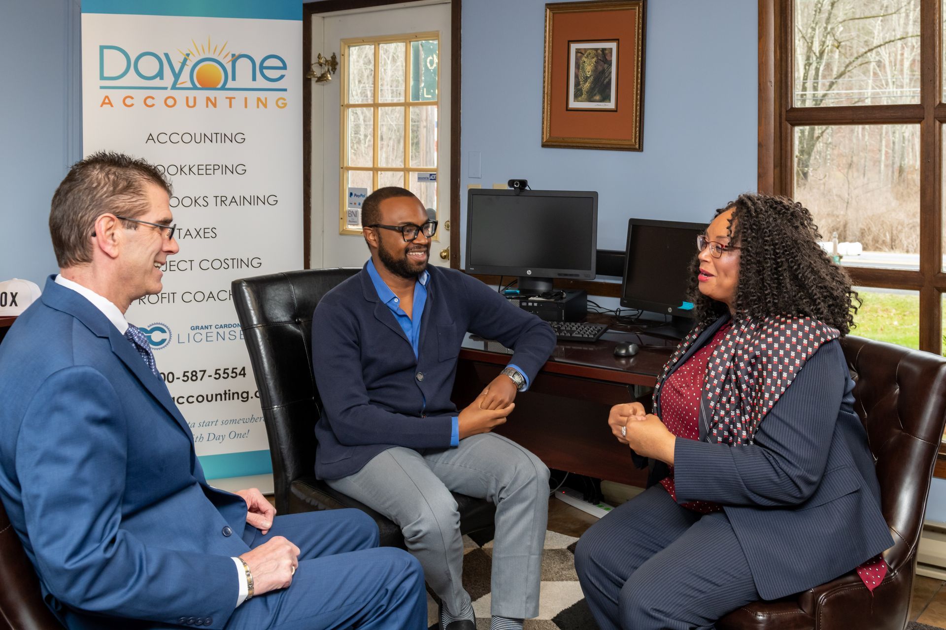 A group of people are sitting in chairs in a room talking to each other.