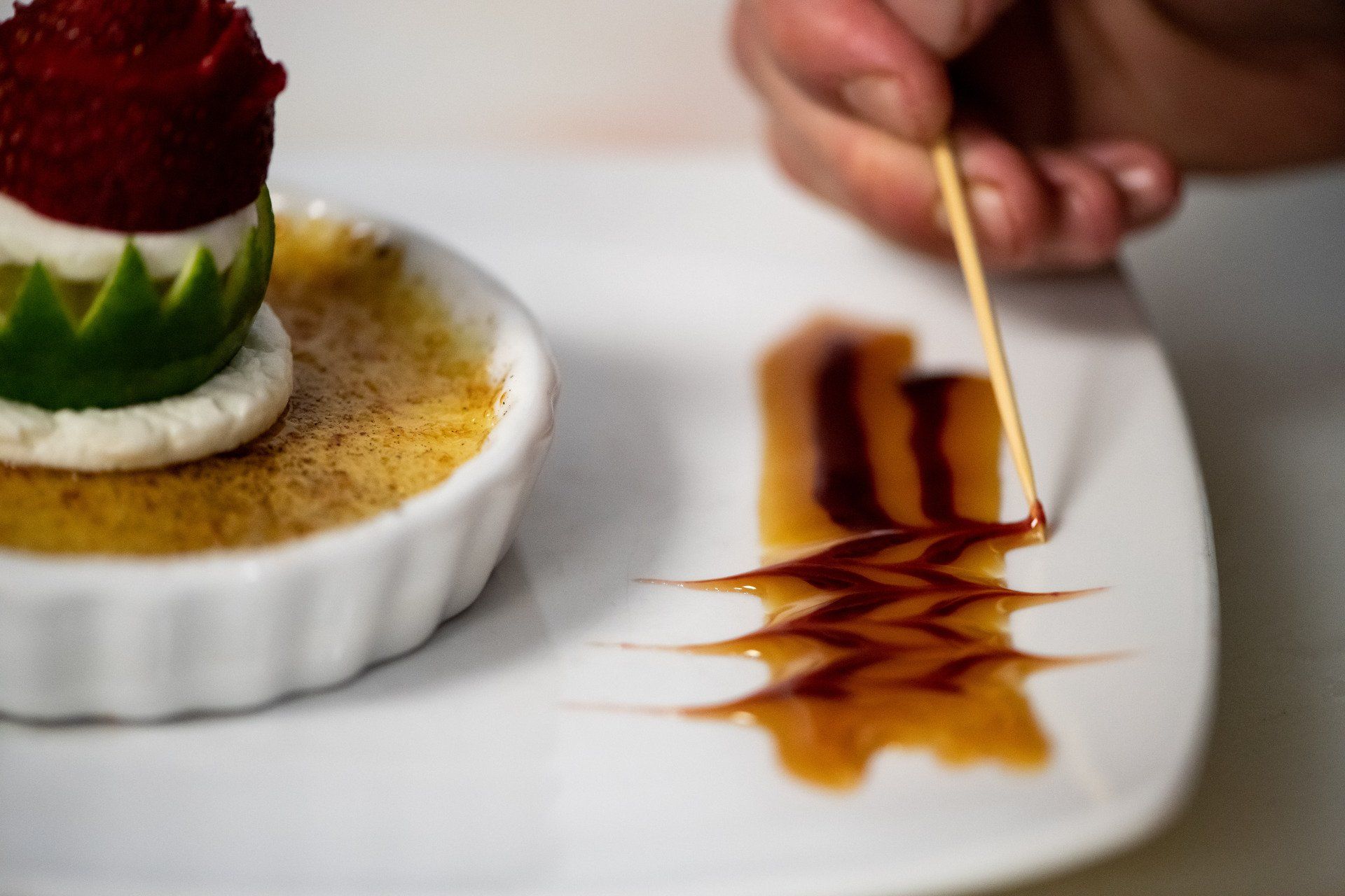 A person is decorating a dessert with a toothpick.