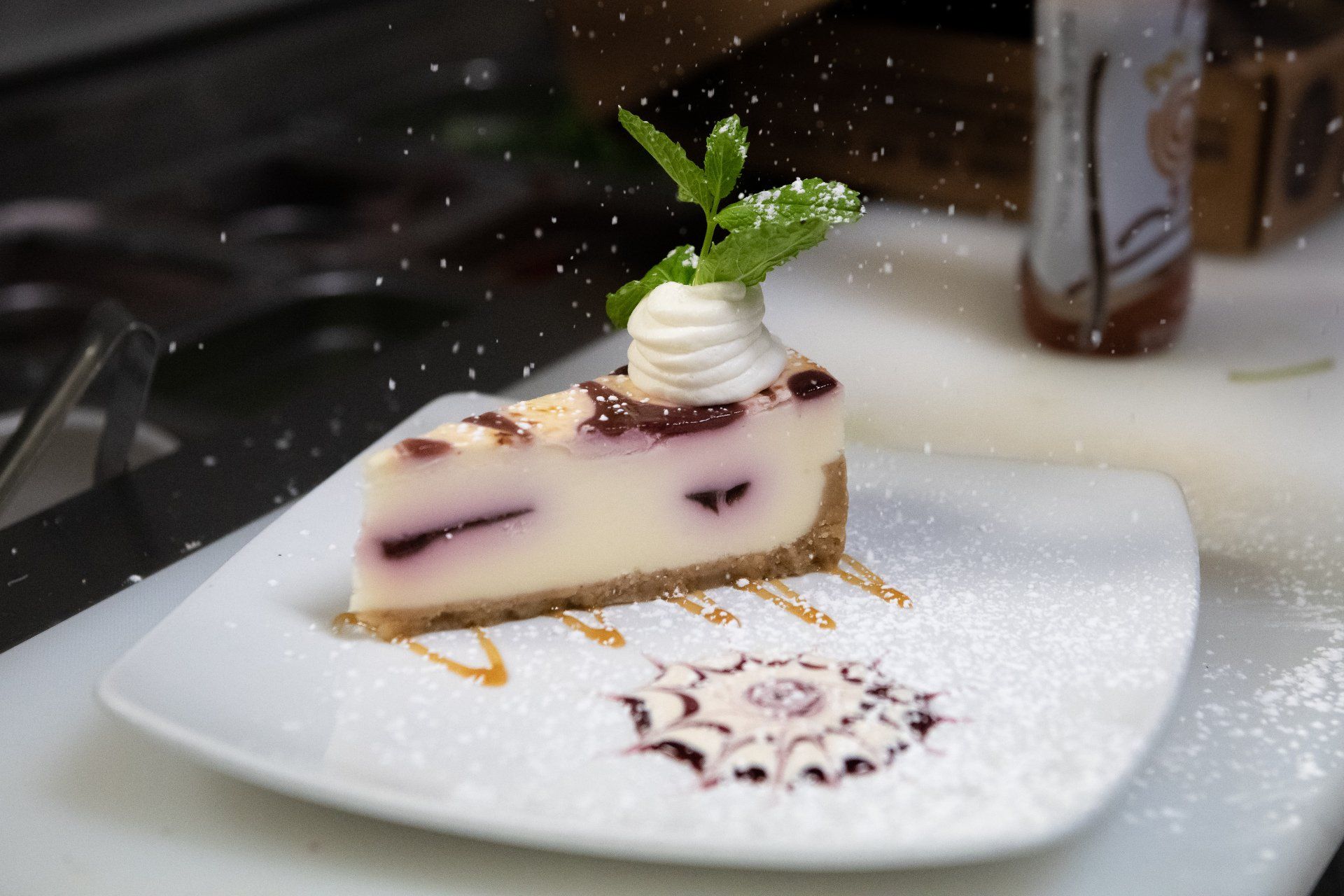 A slice of cheesecake on a white plate with powdered sugar on top.