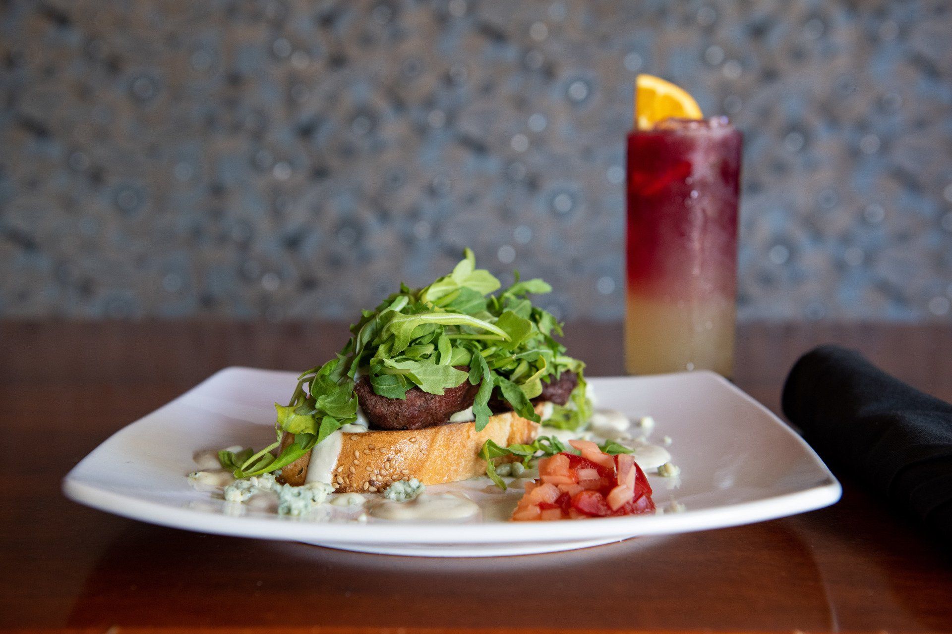 A plate of food with a drink in the background on a table.
