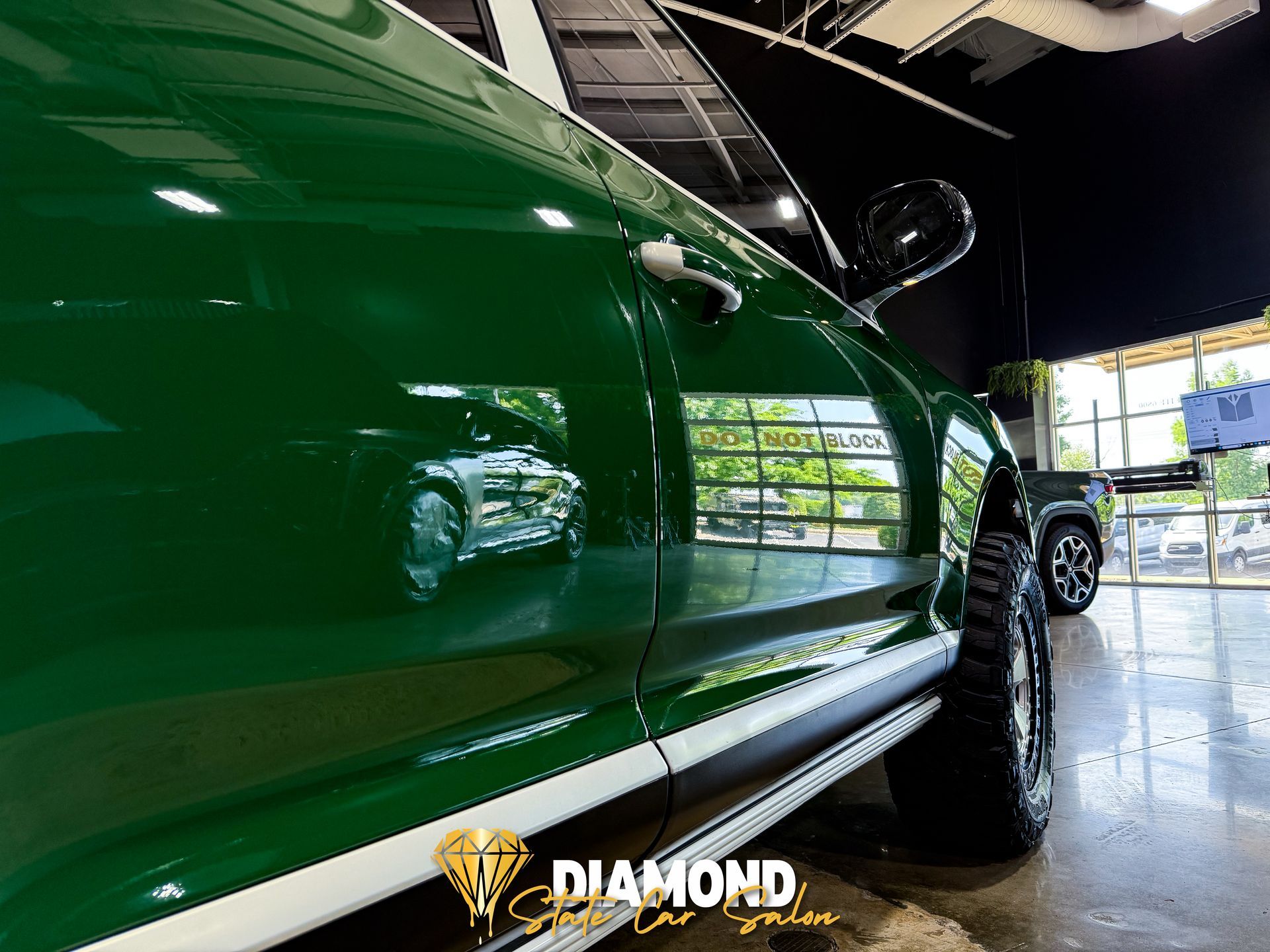 Green car with white stripe, large tires, reflection in shiny paint. Diamond logo.