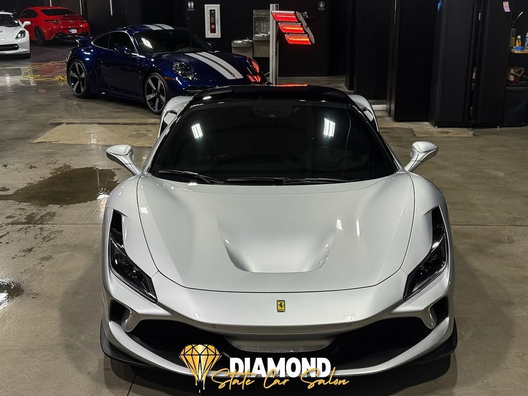 White Ferrari sports car in a garage with other vehicles.