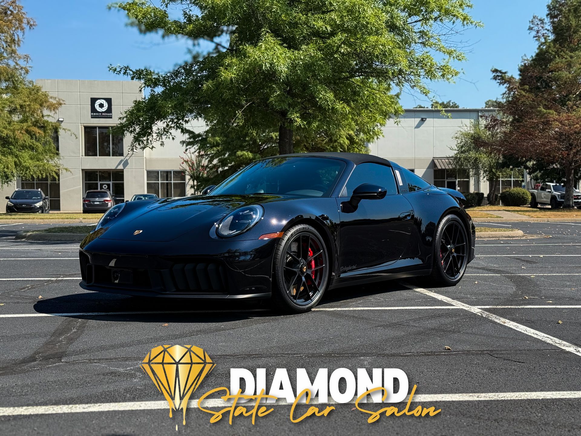 Black Porsche sports car parked in a lot, logo for "Diamond State Car Salon" in the foreground.