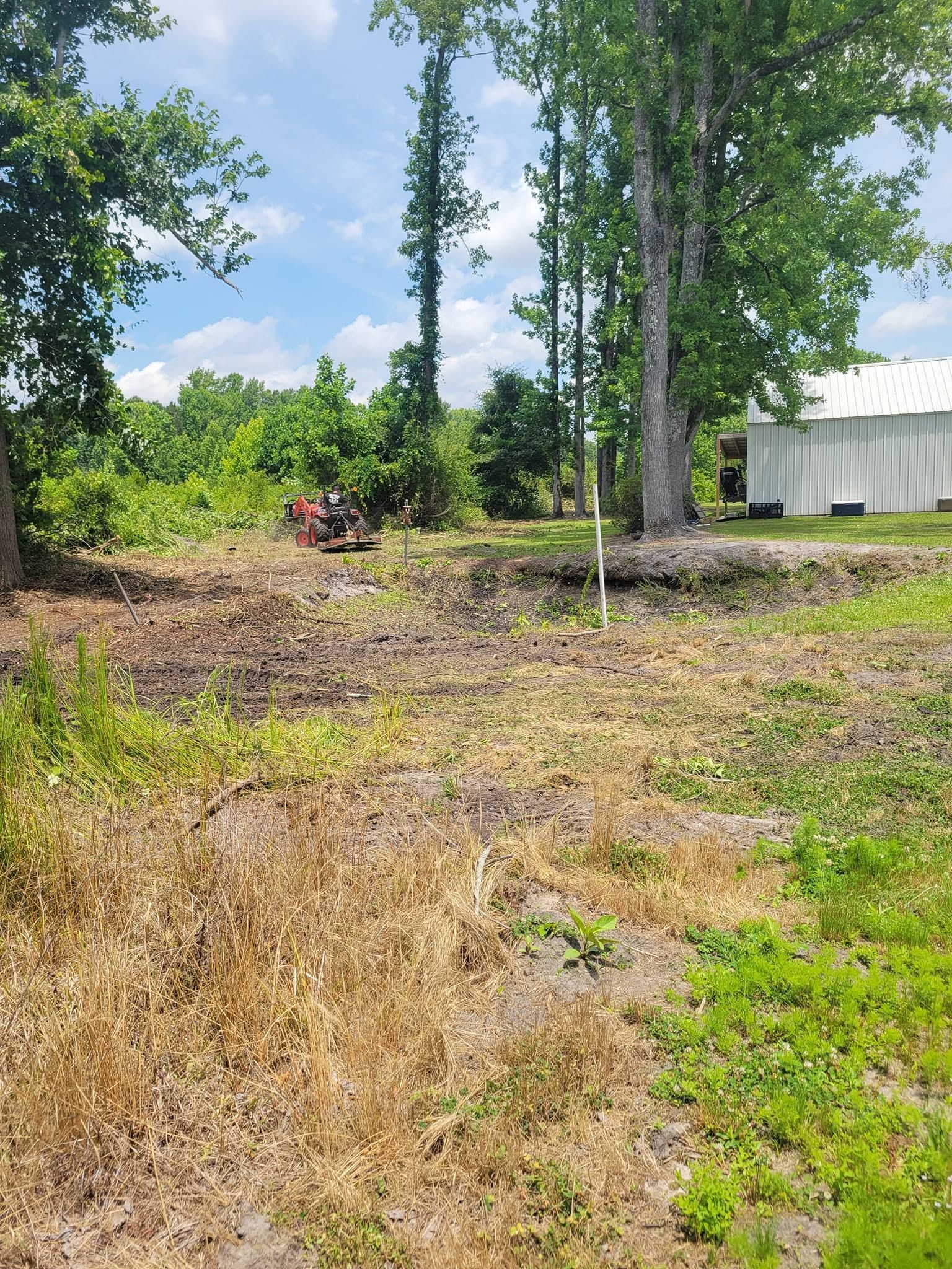A dirt field with trees and a white building in the background.