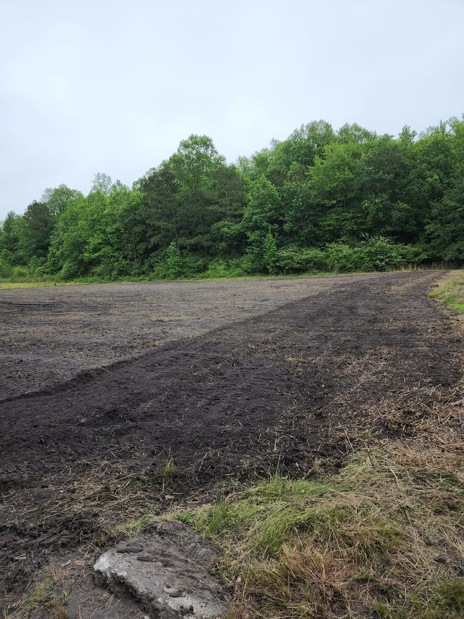 There is a lot of dirt in the middle of a field with trees in the background.