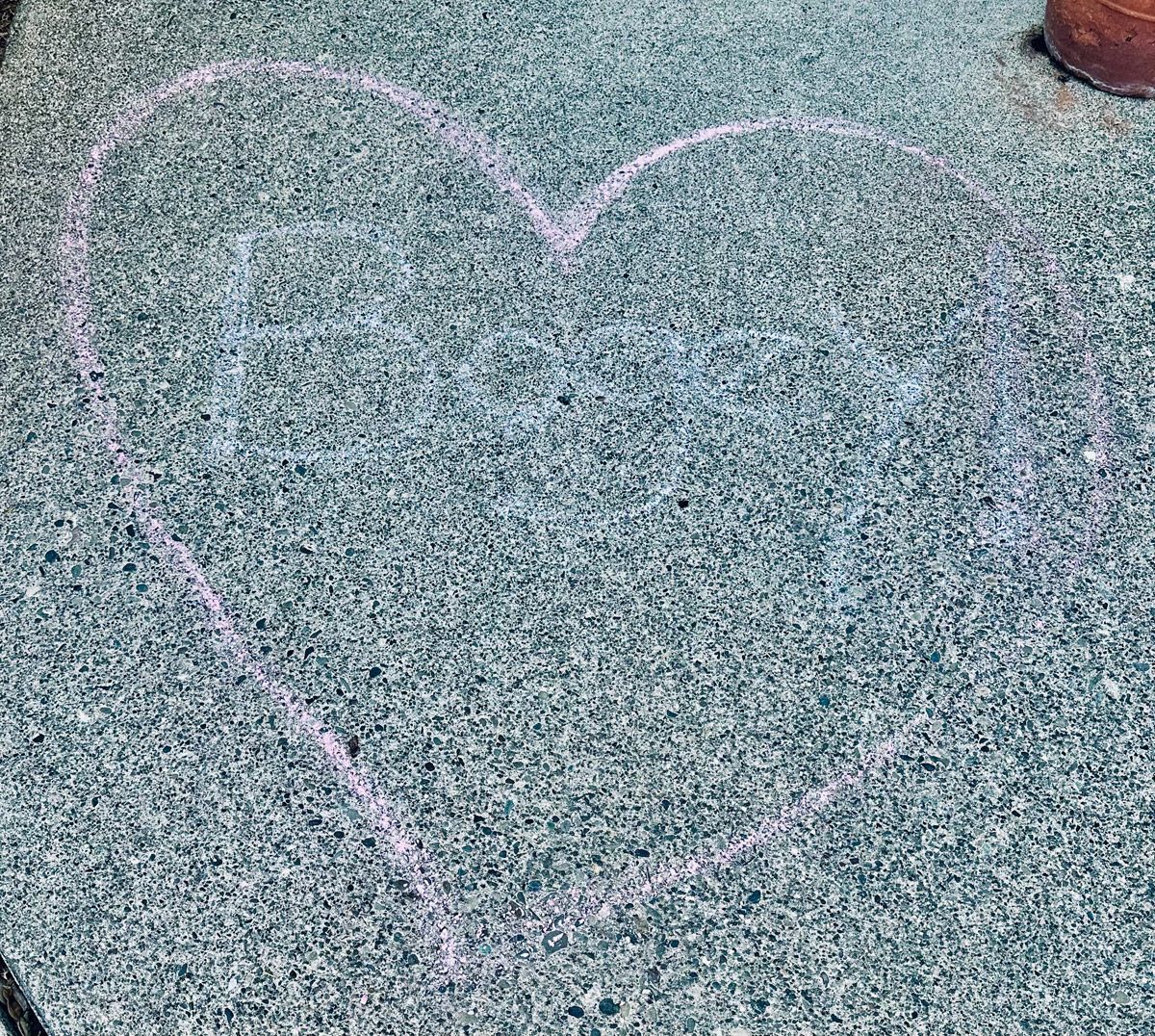 Bogey, the name of a pet who has crossed the rainbow bridge, is written in chalk inside a heart on the sidewalk. 