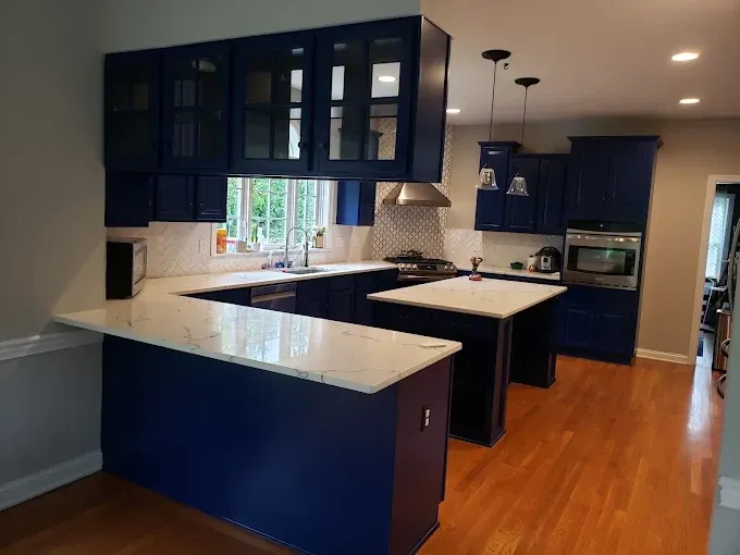 Blue kitchen cabinets with white countertops and wooden floor.