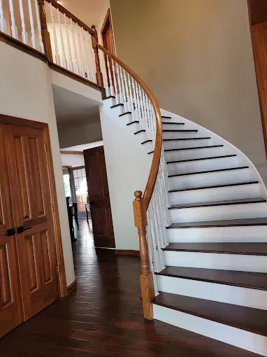 Wooden staircase with white steps and railing in a home's entryway.