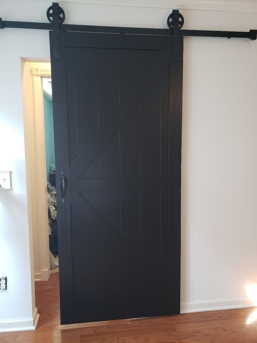 Black sliding barn door on a black rail, interior view.