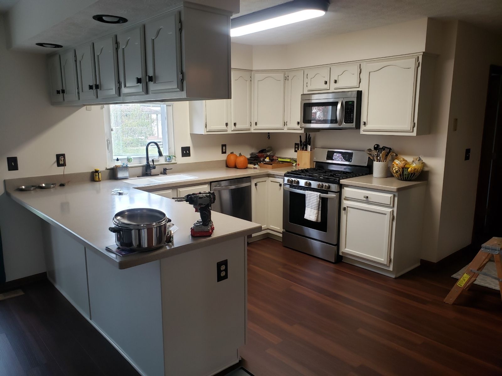Kitchen with white cabinets, stainless steel appliances, and brown floors.