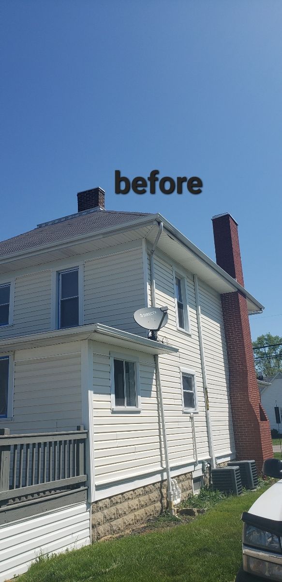 Side view of a two-story white house with a brick chimney under a clear blue sky. 