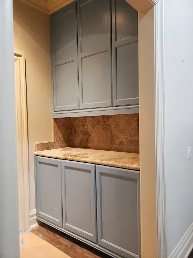 Blue cabinets with a granite countertop in a hallway.