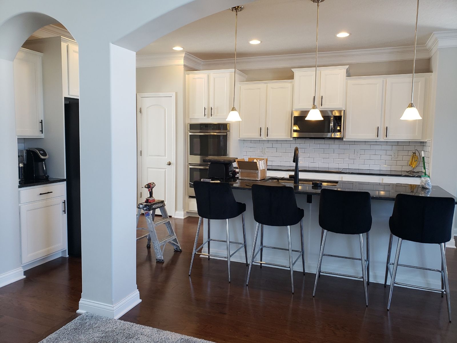 Modern kitchen with white cabinets, black island with stools, and pendant lights.