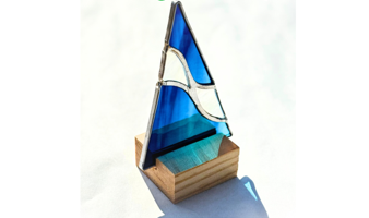 Stained glass art in a shop window, including a face, tree, and other colorful designs.