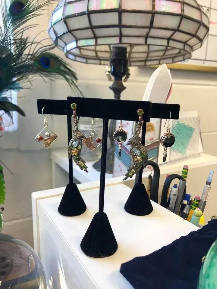 Earrings on black velvet display stands, under a Tiffany-style lamp.
