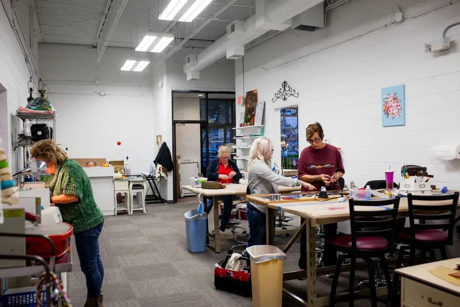 People craft at tables in a brightly lit studio.