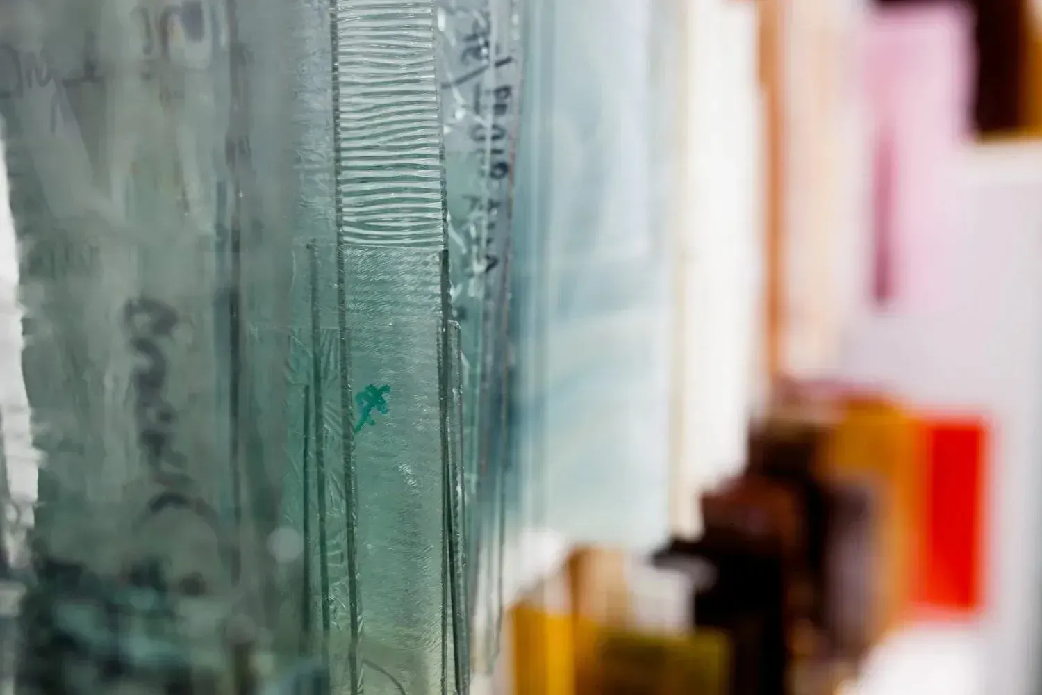 Stack of translucent glass microscope slides in various colors.