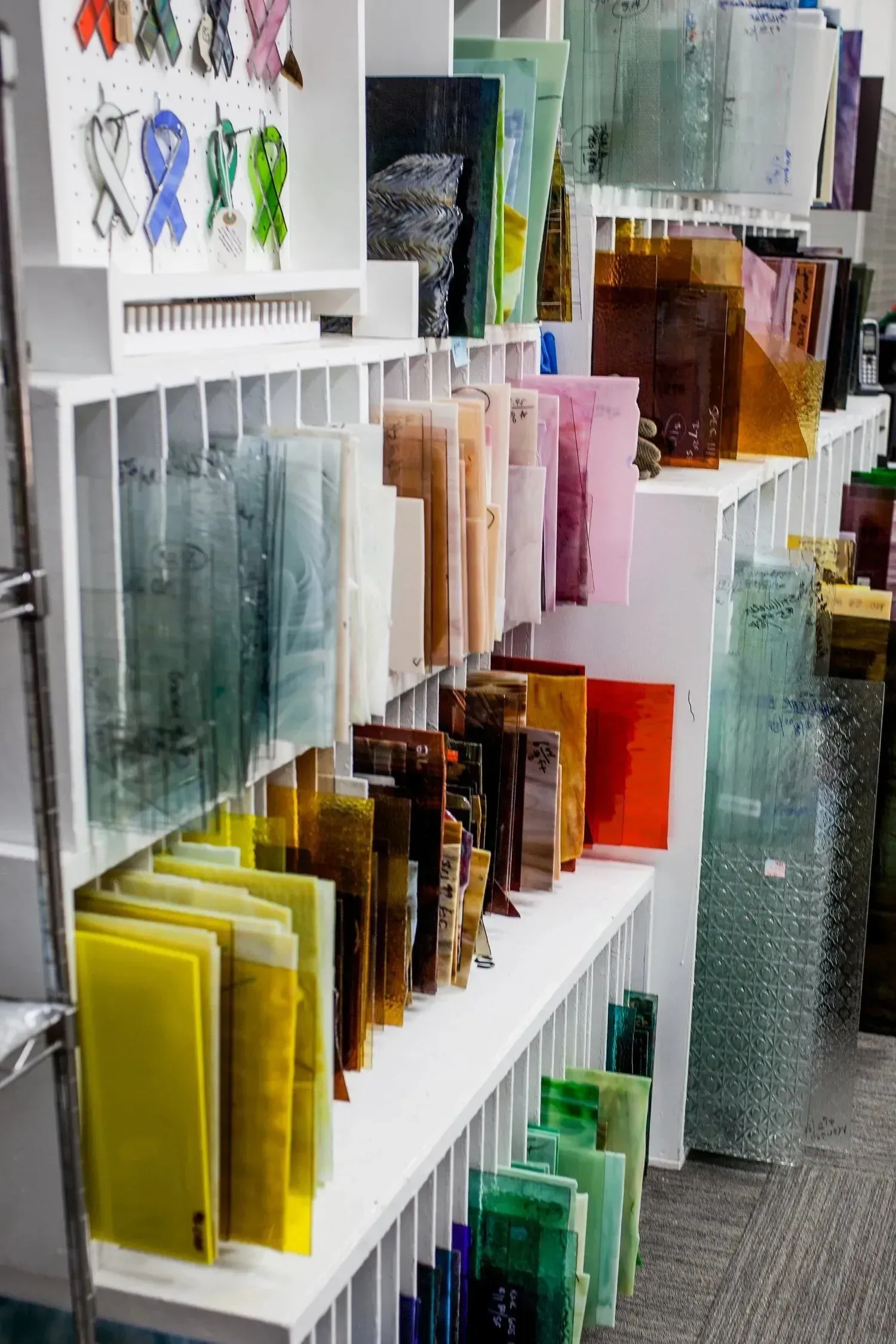 Shelves displaying various colorful sheets of glass in a store.
