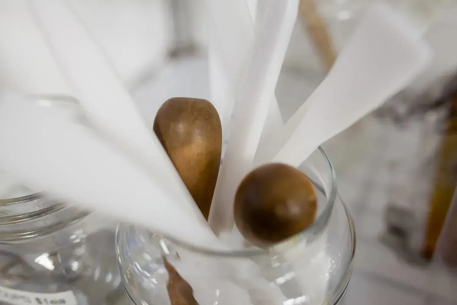 Glass jar with brown wooden items and white paper cones.